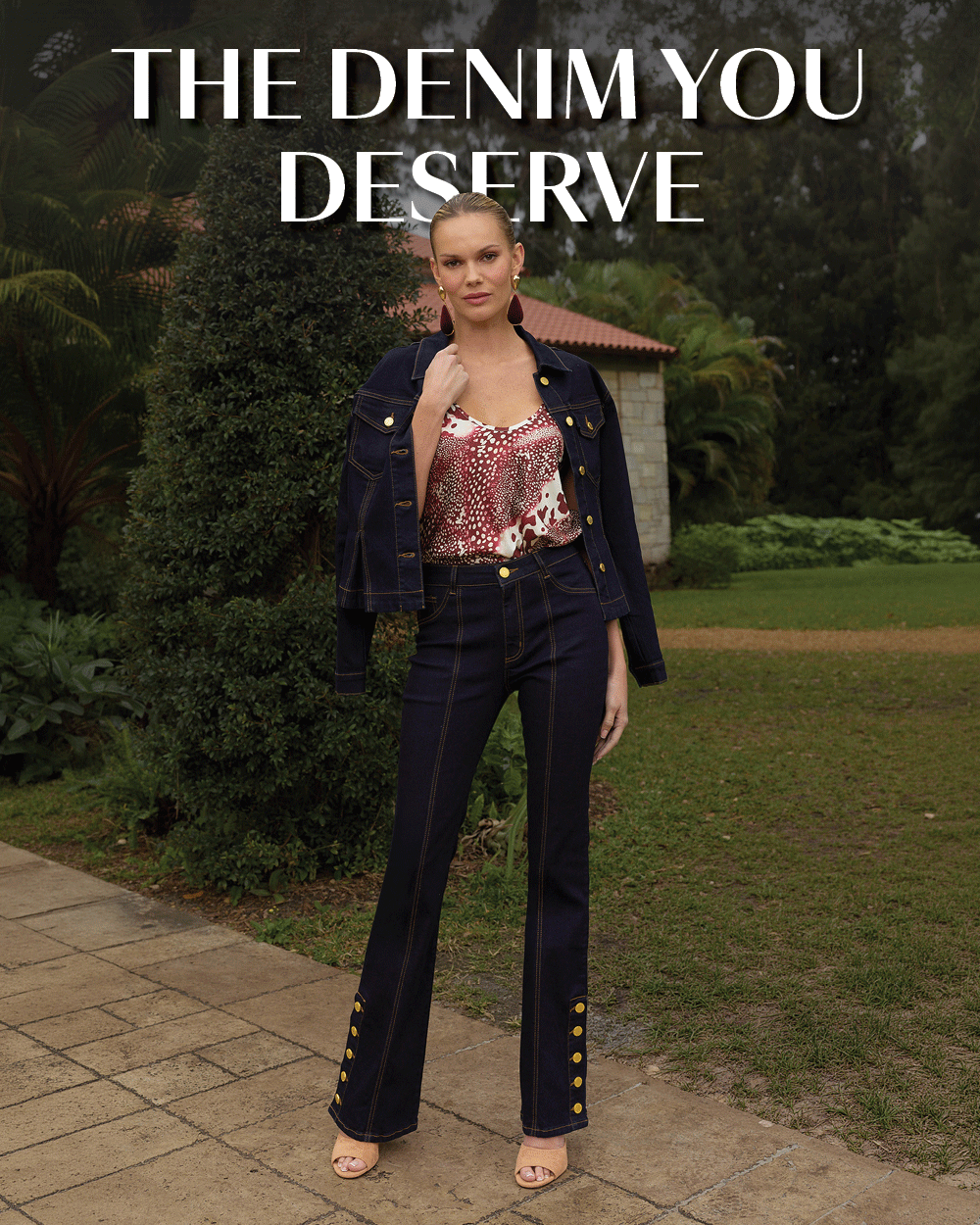 The Denim You Deserve. A gif of a model in the Indigo Bethanie Denim Jacket, Garnet Crush Yara Silk Camisole, and Indigo Vernonica Button Jean posed in a lush green garden.