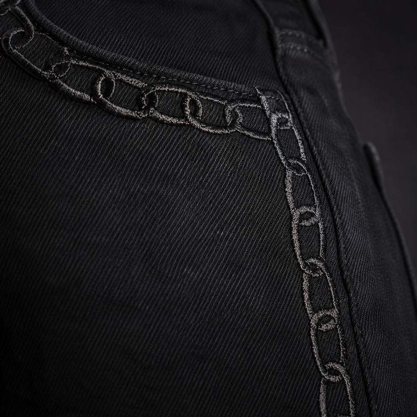 Close-up of the Celeste Slim Palazzo Jean in Black Chain: a chain motif embroidered link by link in black thread along the seam of black denim