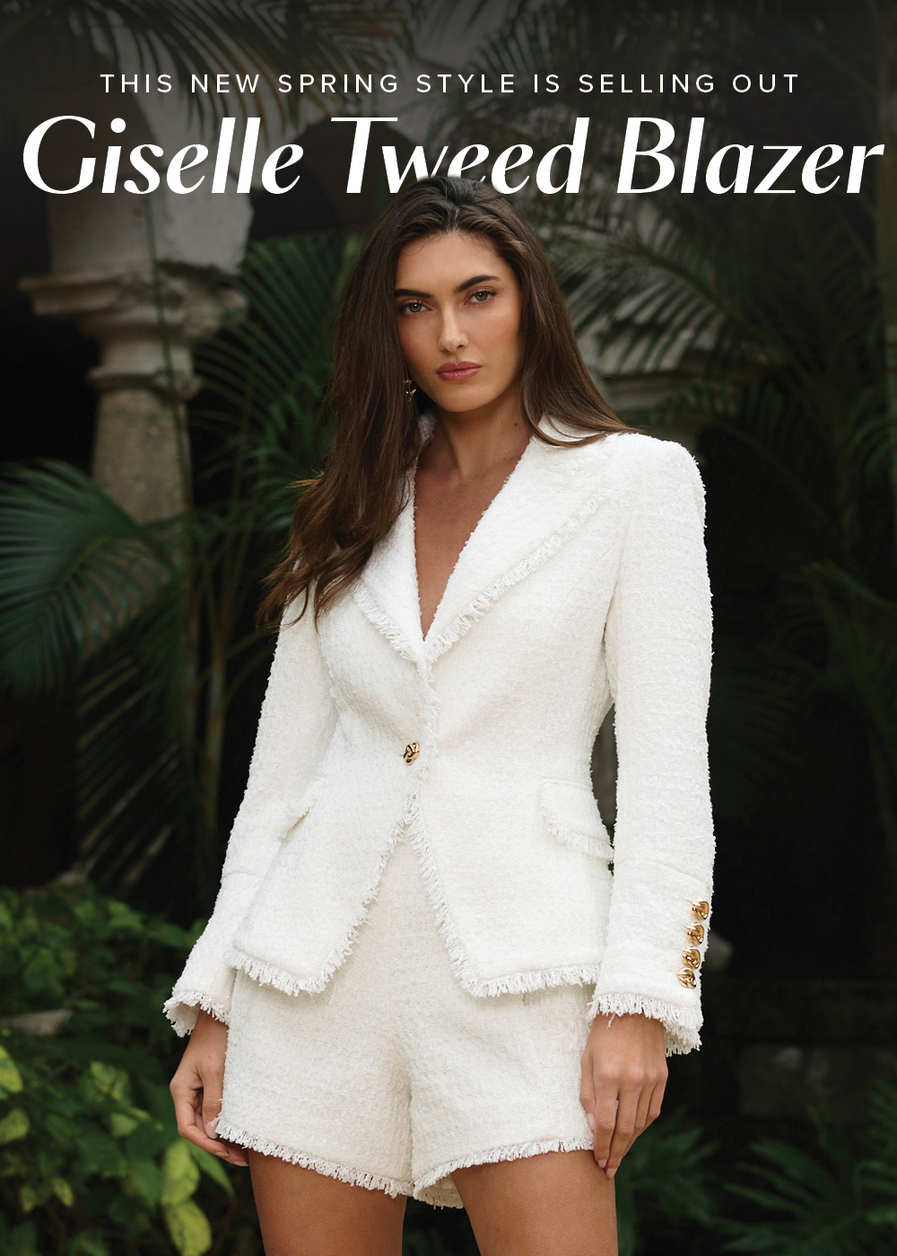 This New Spring Style is Selling Out. Giselle Tweed Blazer. An image of a model posed in a lush garden with lots of greenery wearing the White Giselle Single Breasted Tweed Blazer and White Tamara Tweed Button Short.