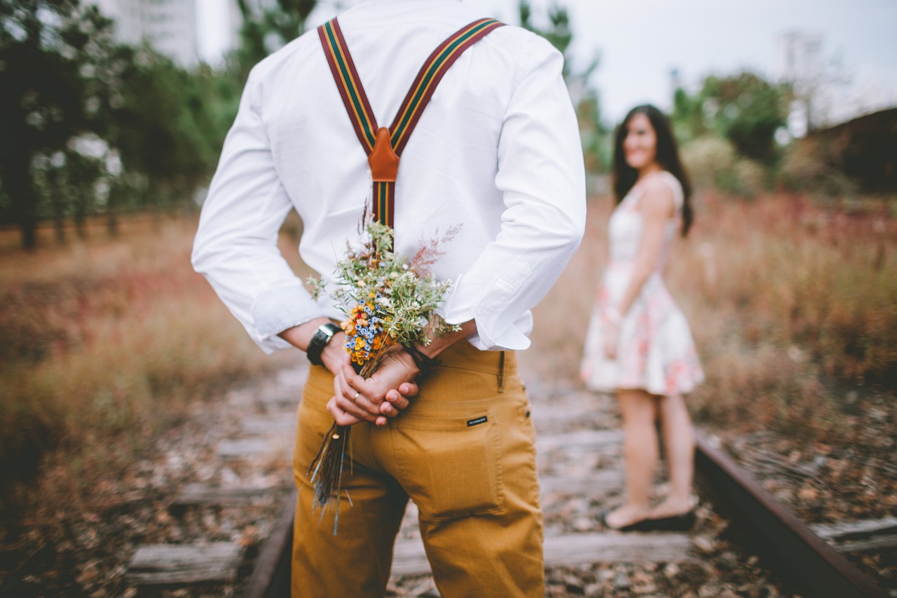 surprise gift man courting woman with flowers behind his back