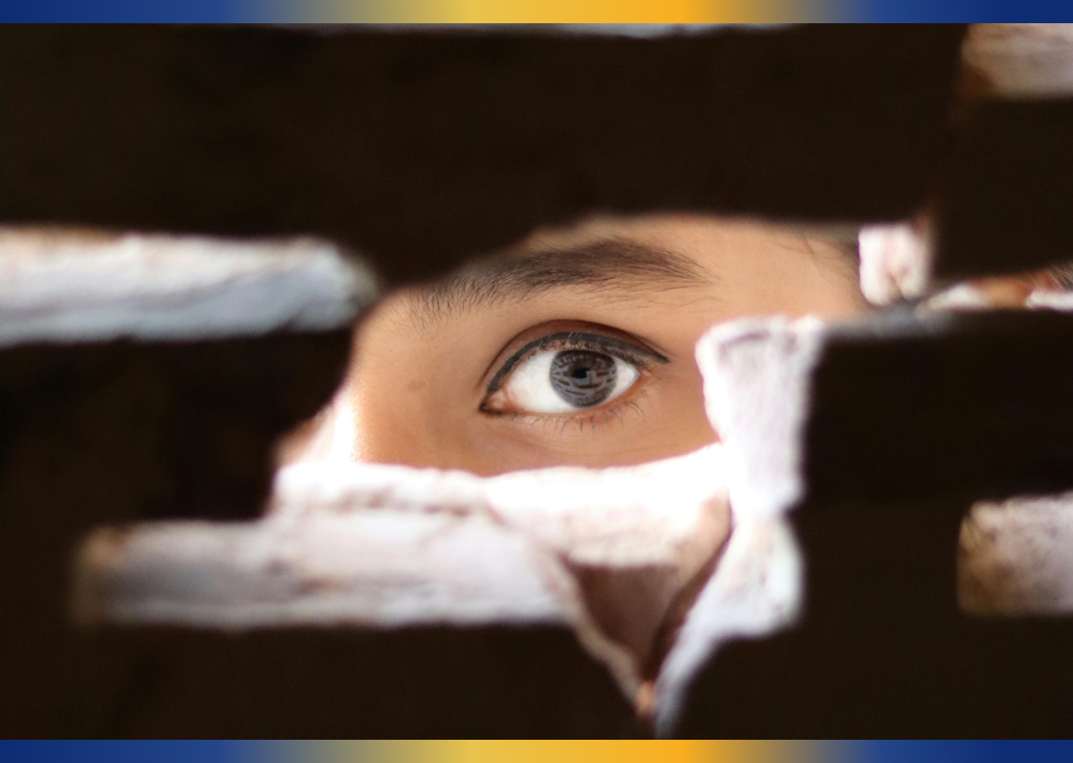 close up of person's eye looking through a hole in a wall