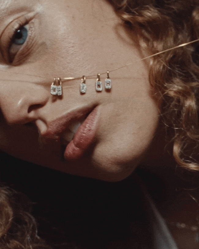 Close-up gif of a woman holding a delicate, personalized necklace including diamond initial tags