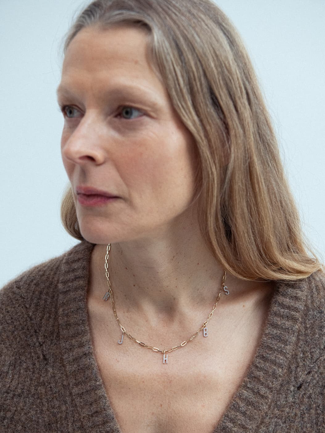 a woman wearing a gold necklace personalised with diamond letters