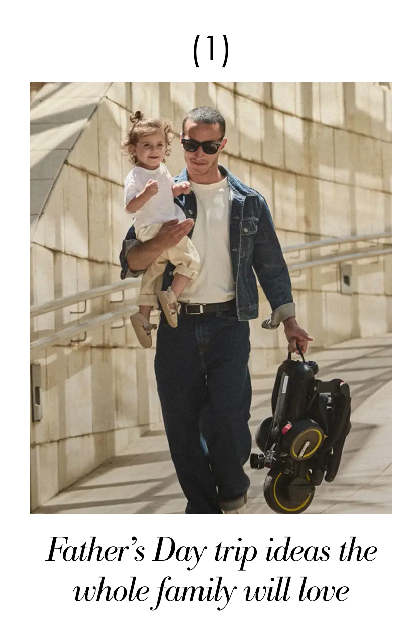 Man holding a toddler and carrying a Liki Trike during an outdoor family outing.