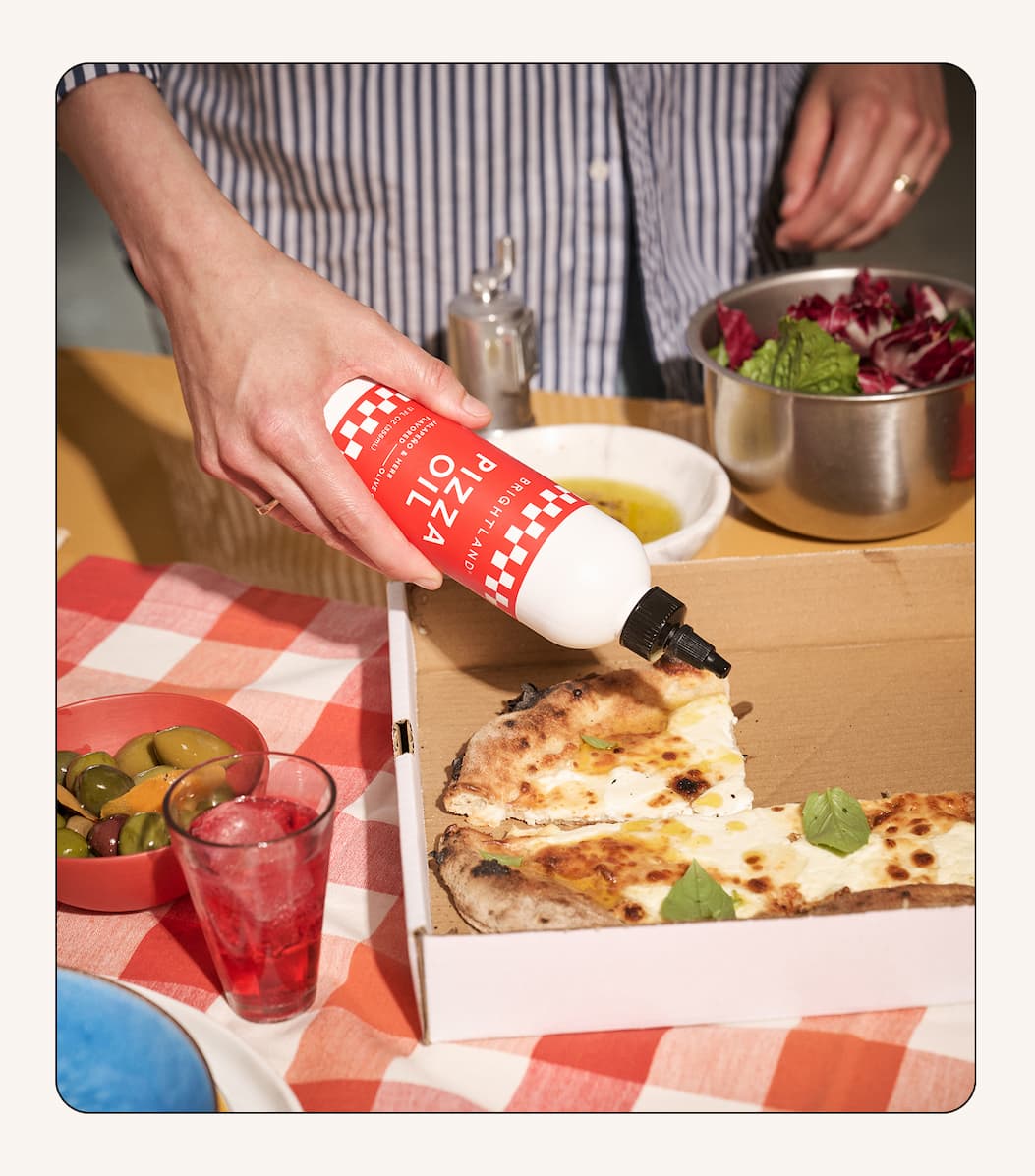 Image of pizza oil being squeeze on a takeout cheese pizza