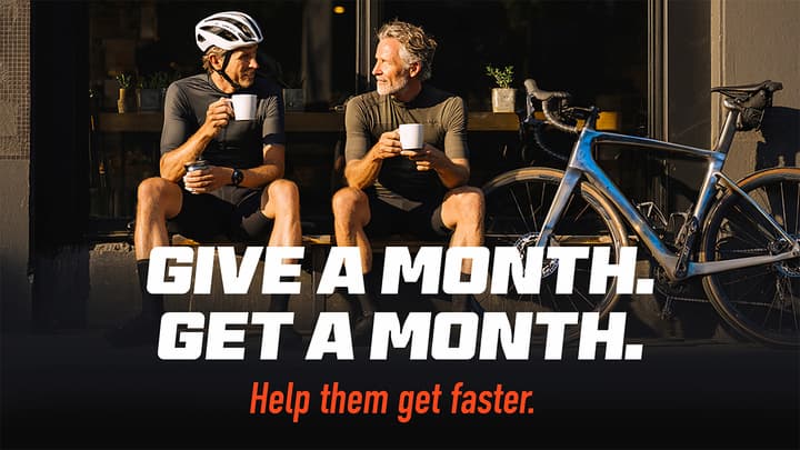 Two cyclists take a break with coffee, with text promoting a "Give a month, get a month" offer.