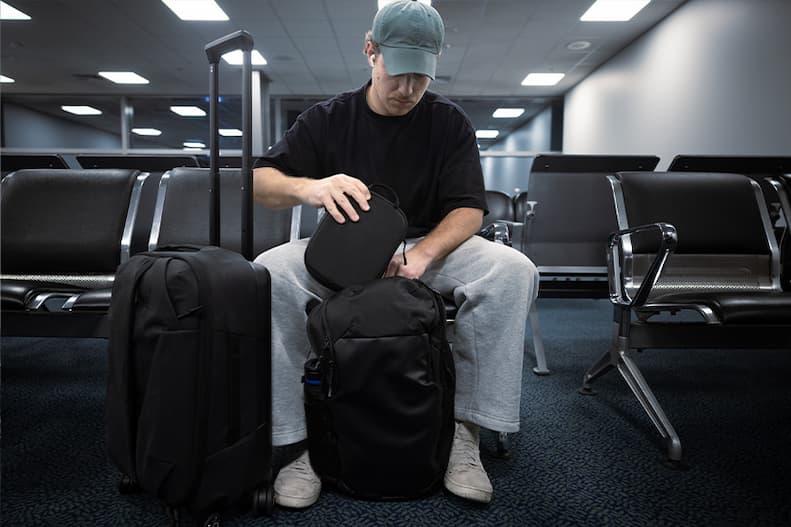 Traveller packing a Quad Lock Travel Organizer into the Traverse Backpack at an airport.