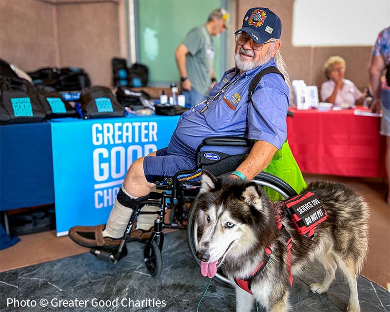 Veteran in a wheelchair with a service dog beside him.
