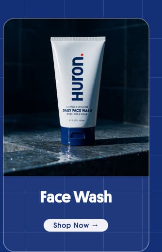 Huron Daily Face Wash tube on wet stone shower ledge with "Shop Now" button.