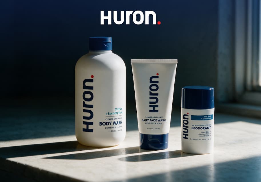 uron body wash, face wash, and deodorant lined up on a marble surface with dramatic lighting.