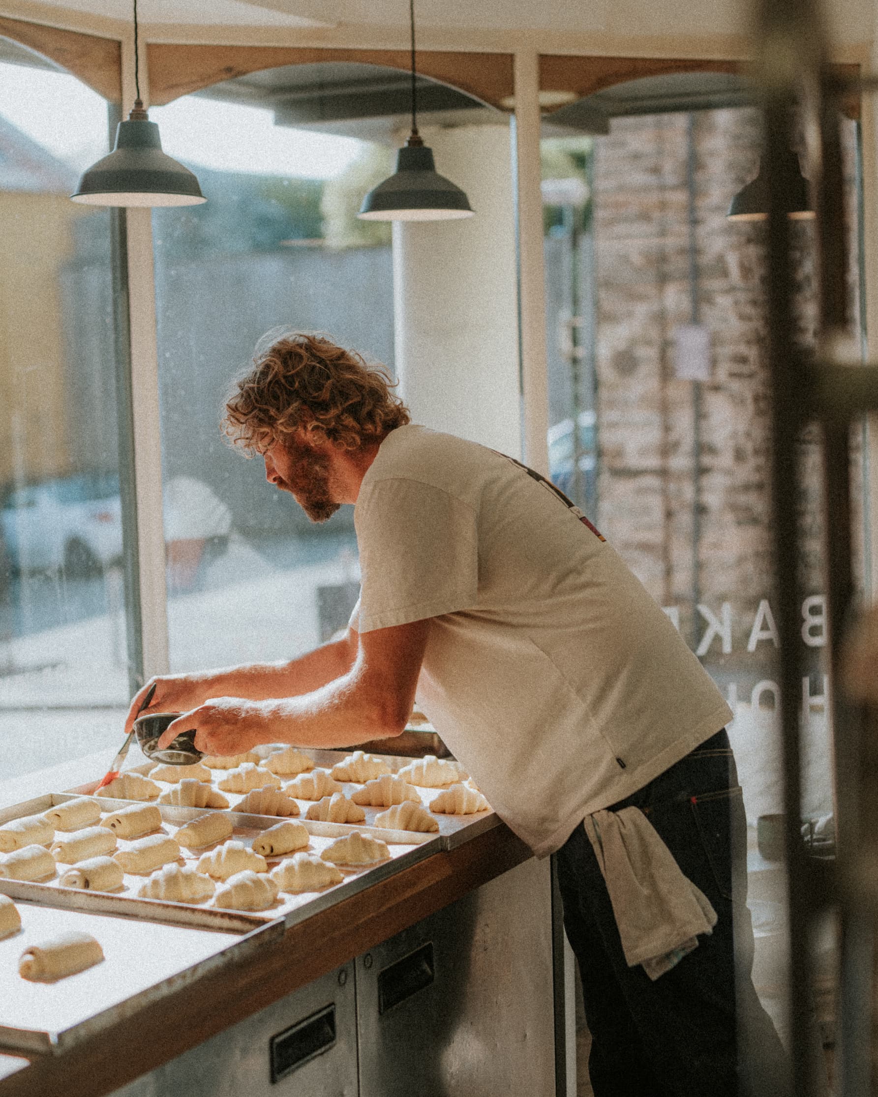 Baker brushing butter on pastries.