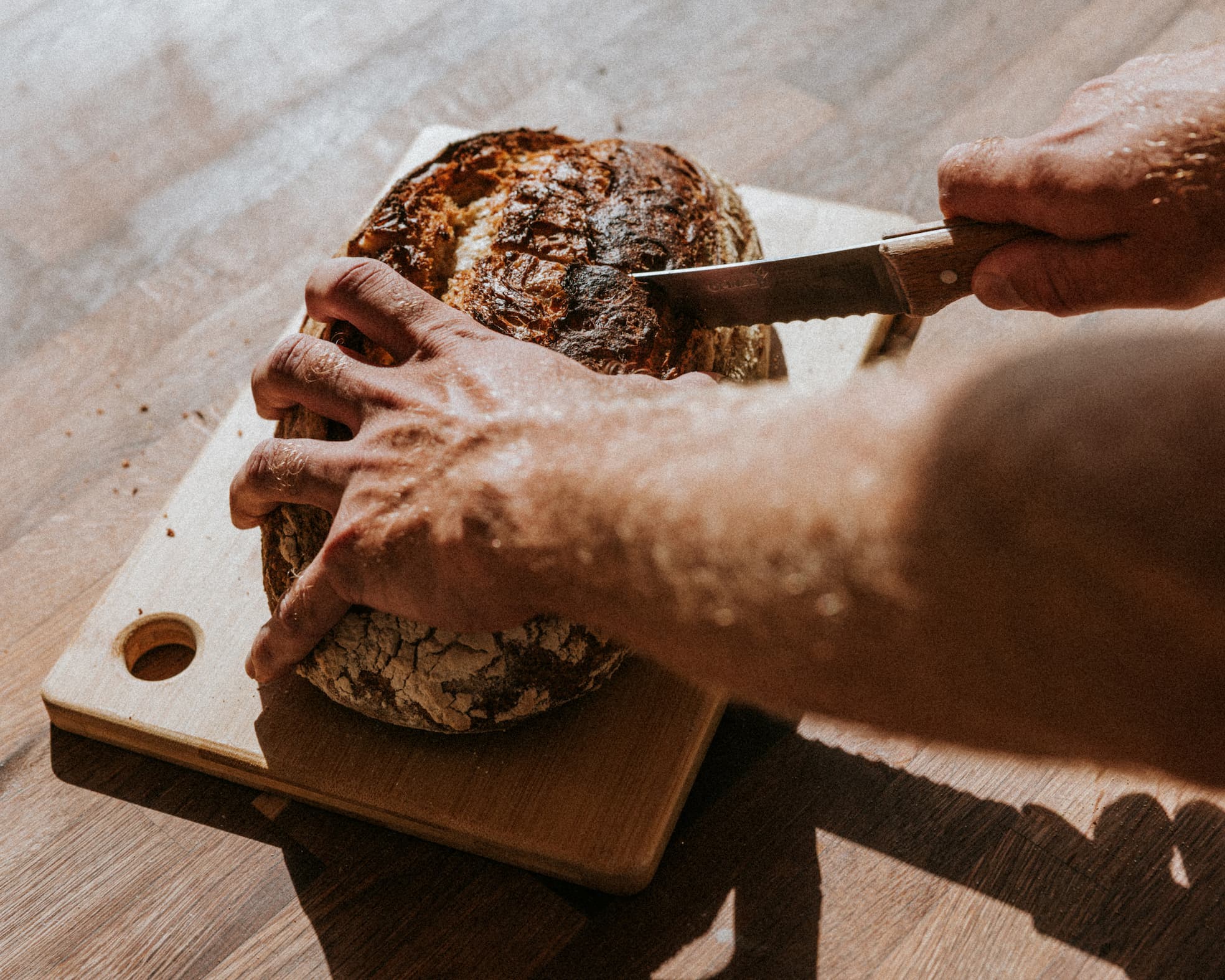 Knife cutting into a loaf of bread.