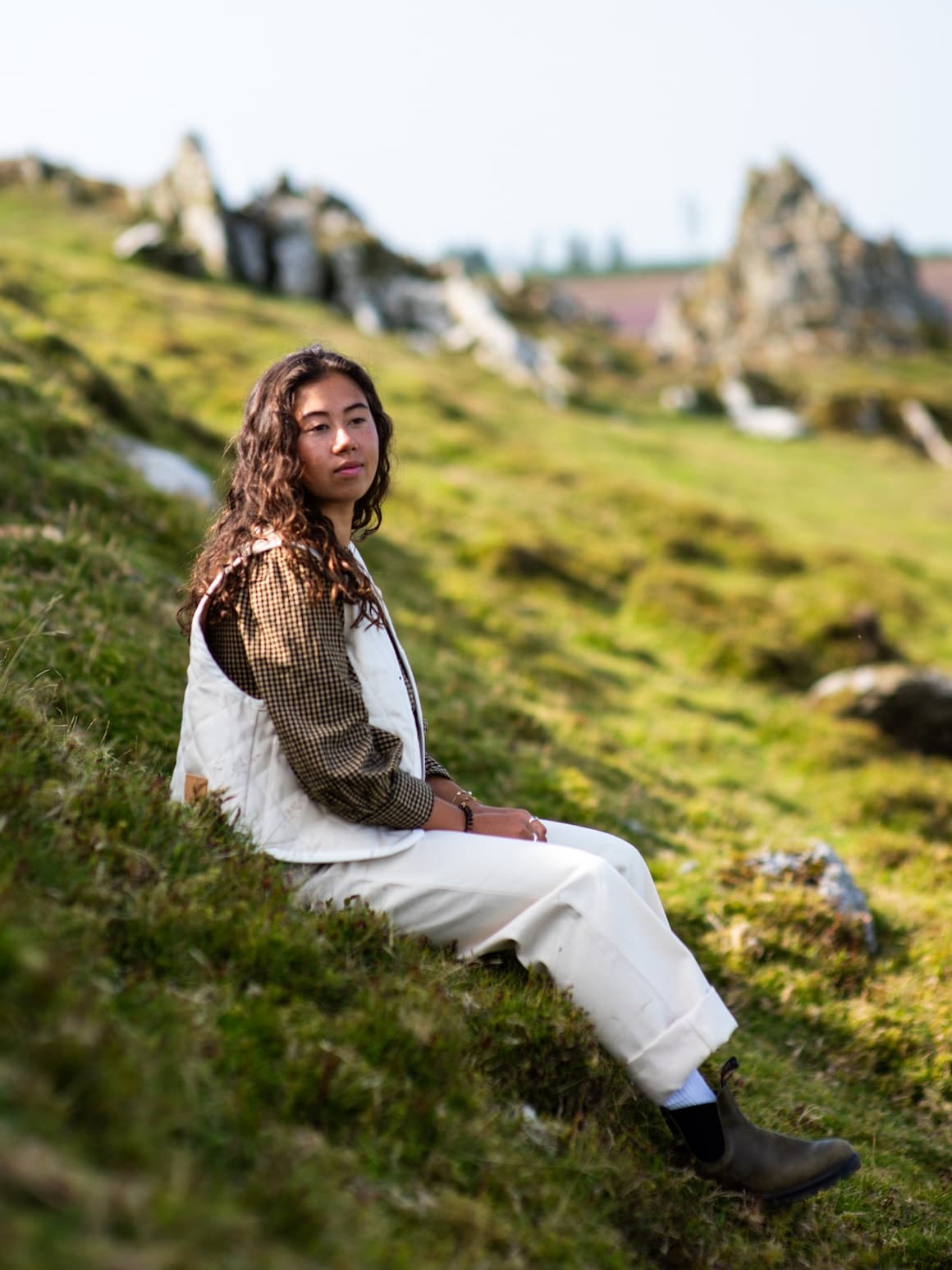 A young woman sitting in a field and a close up of jeans.