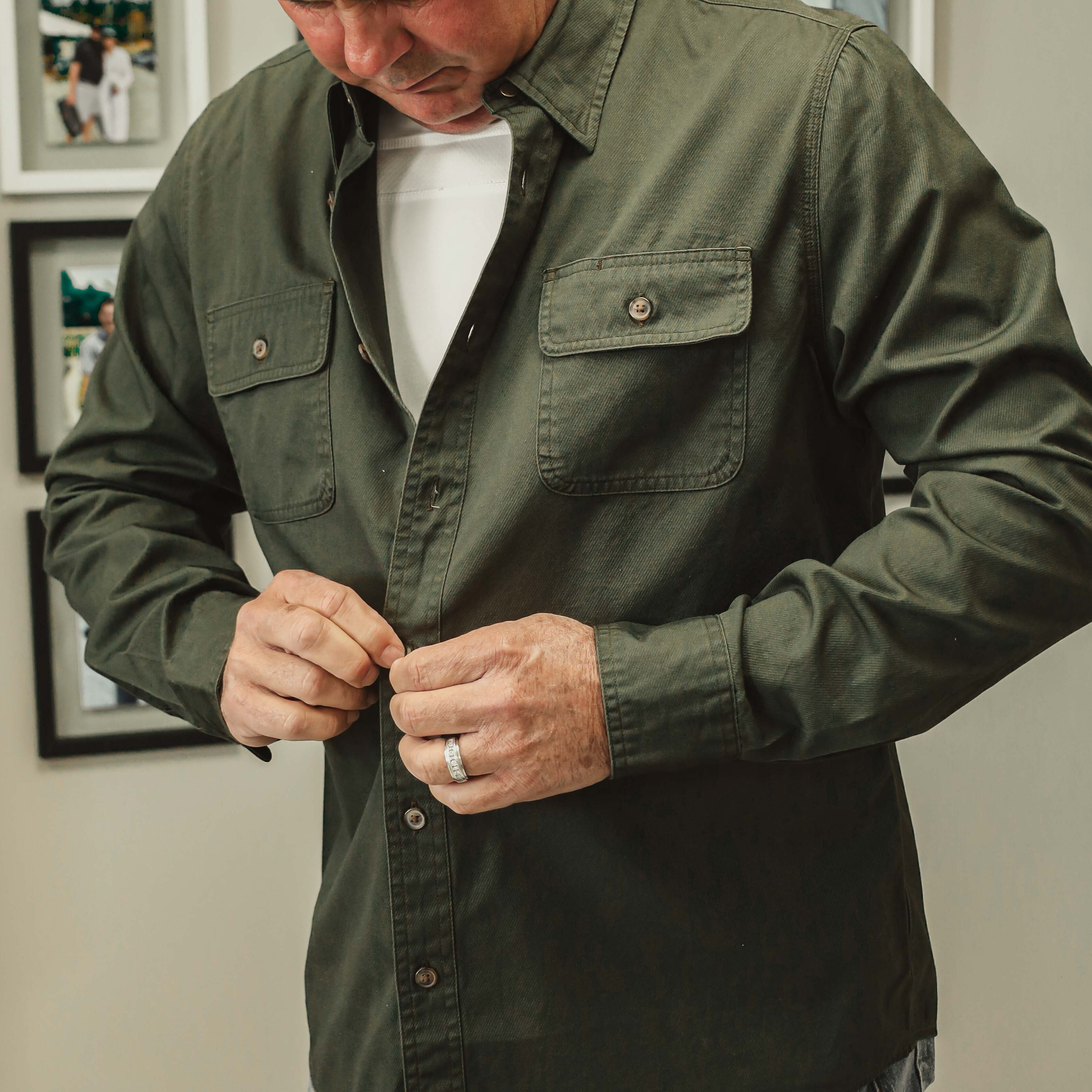 mean buttoning loose dark green shirt over white under shirt