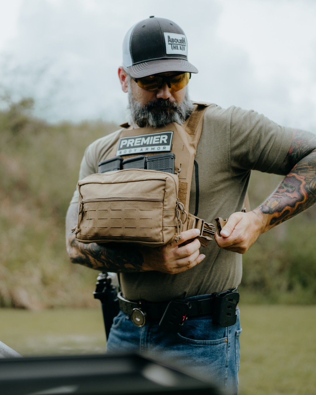 man adjusting brown plate carrier with maap pouch on front