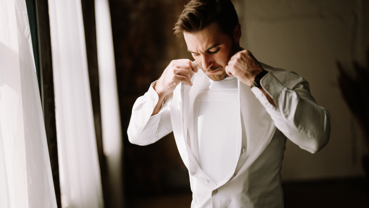 man putting dress shirt on over armor t-shirt