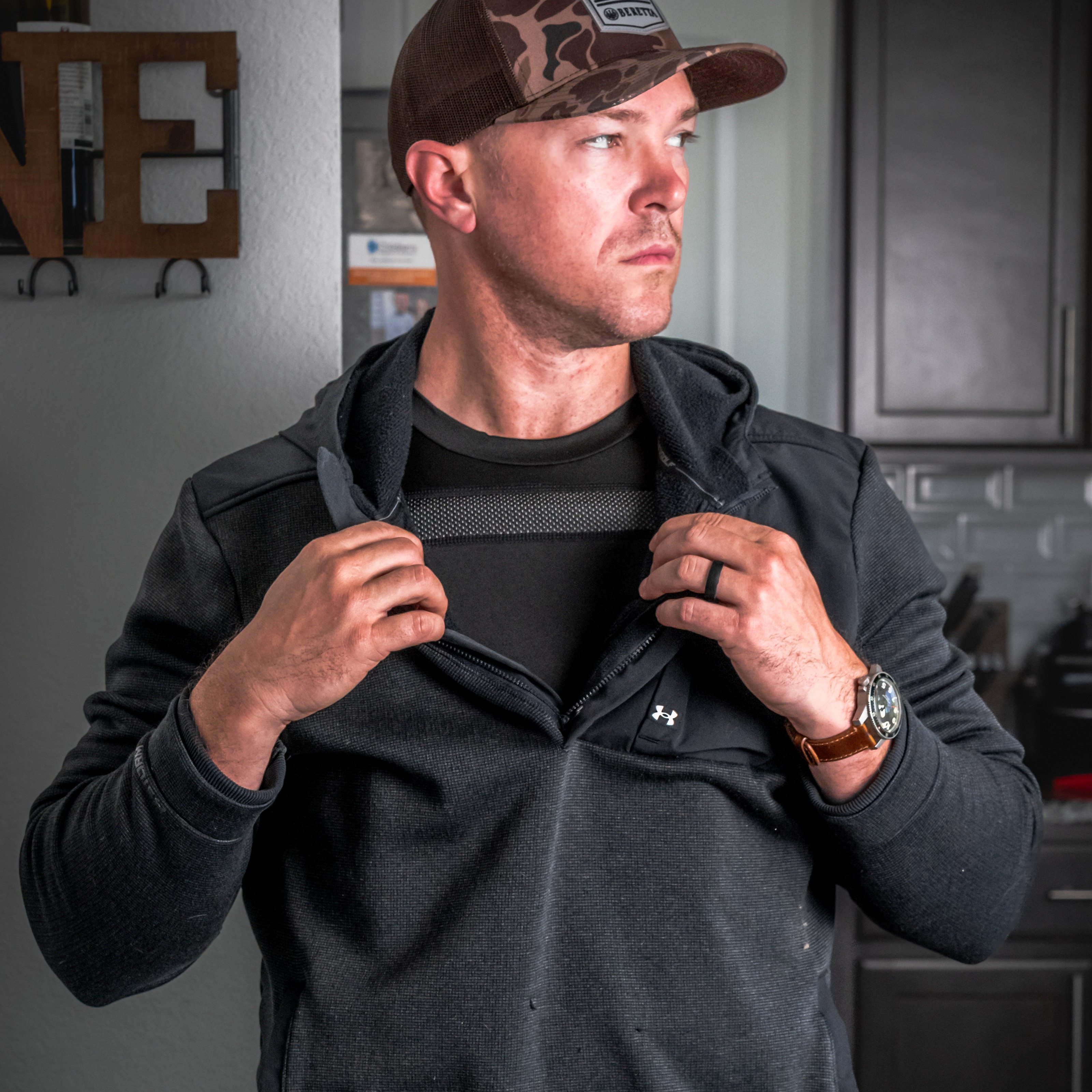 mean wearing zip up hoodie showing armor vest under