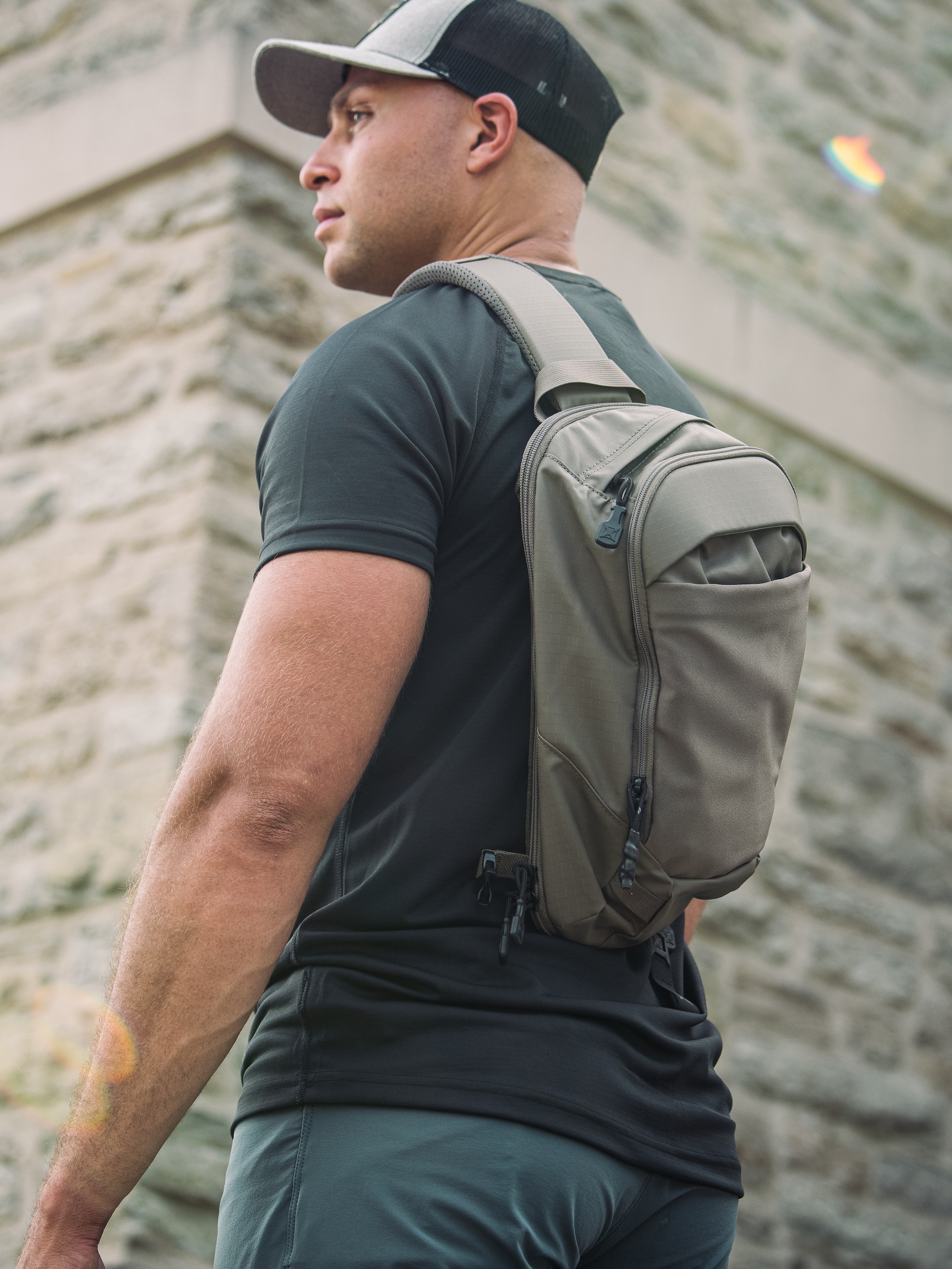 man outside wearing vertx ghost sling backpack in grey