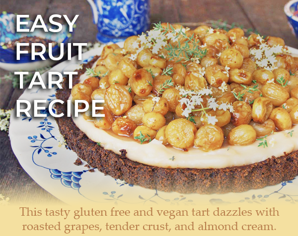Photo of a fruit tart on a white and blue plate. The overlay text reads: "Easy Fruit Tart Recipe. This tasty gluten free and vegan tart dazzles with roasted grapes, tender crust, and almond cream."
