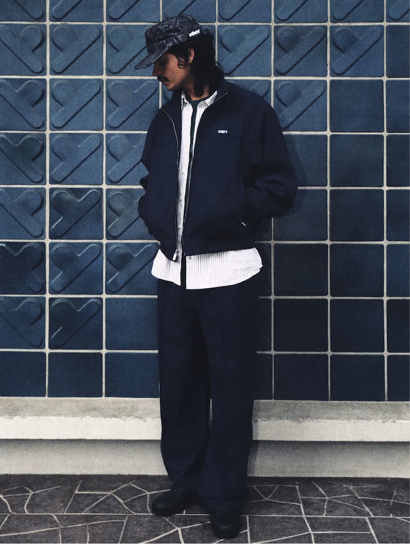 Men Model Standing on fron of blue wall tiles wearing Obey Bottoms from Fall Collection