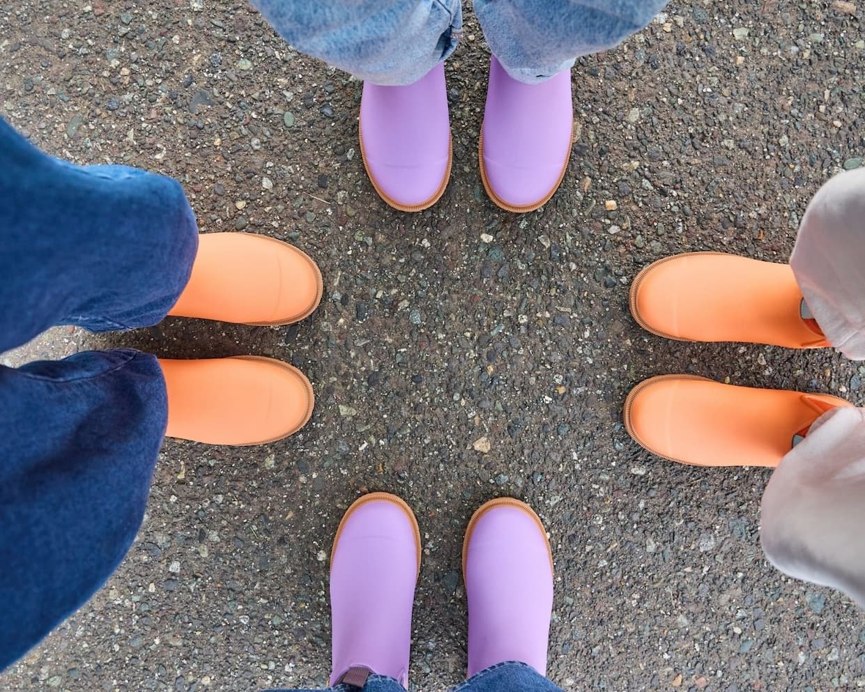 Group of people standing in a circle with colourful boots