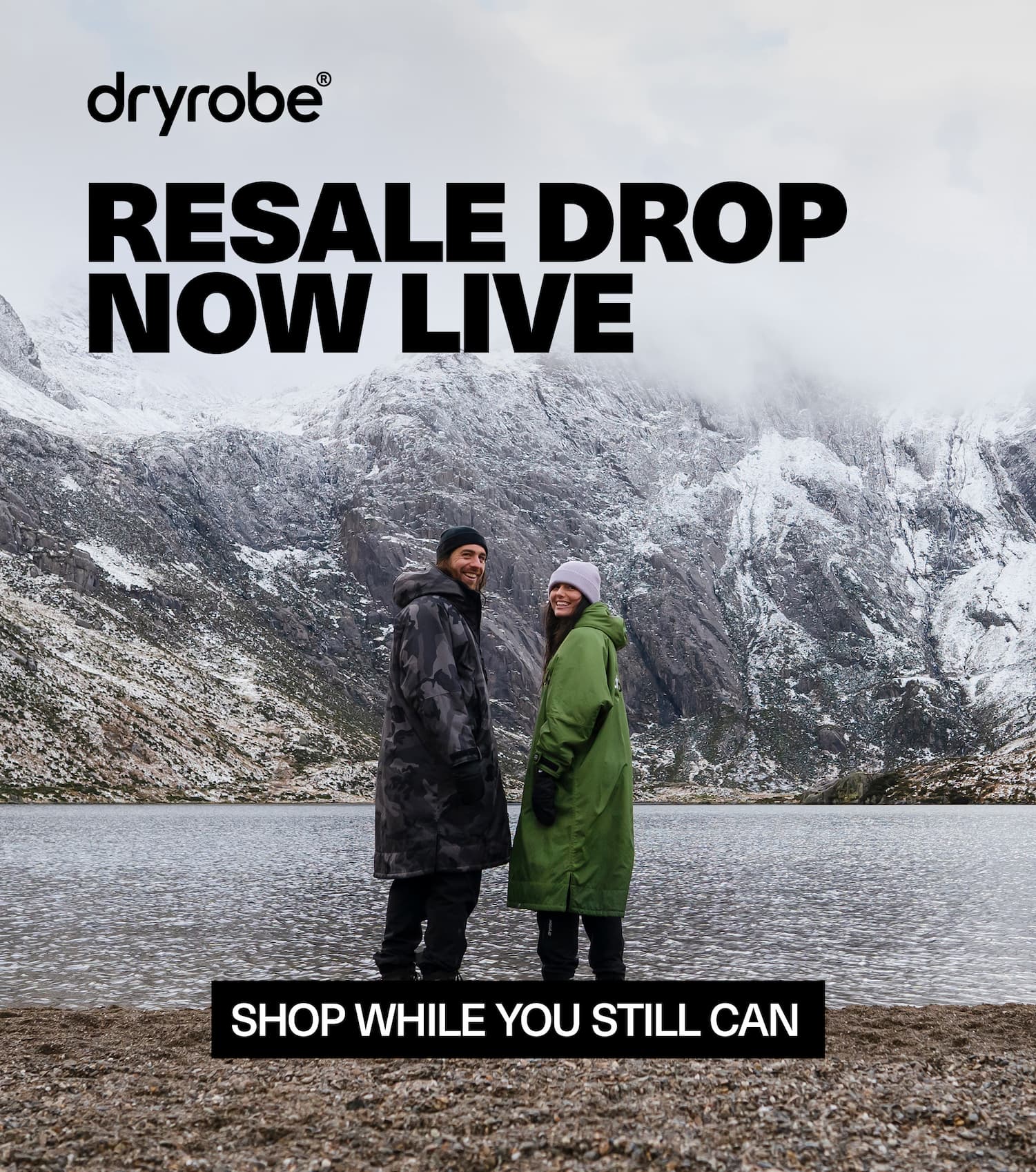 Male and female in the Welsh mountains wearing changing robes beside a lake