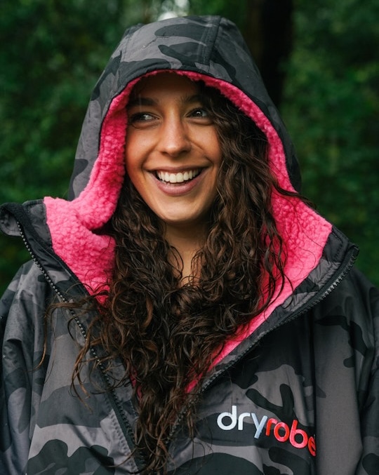 Woman in dryrobe® Advance Long Sleeve Black Camo Pink with hood up while smiling