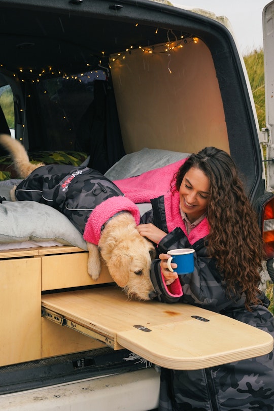 Woman and dog enjoying a hot drink from the back of the van