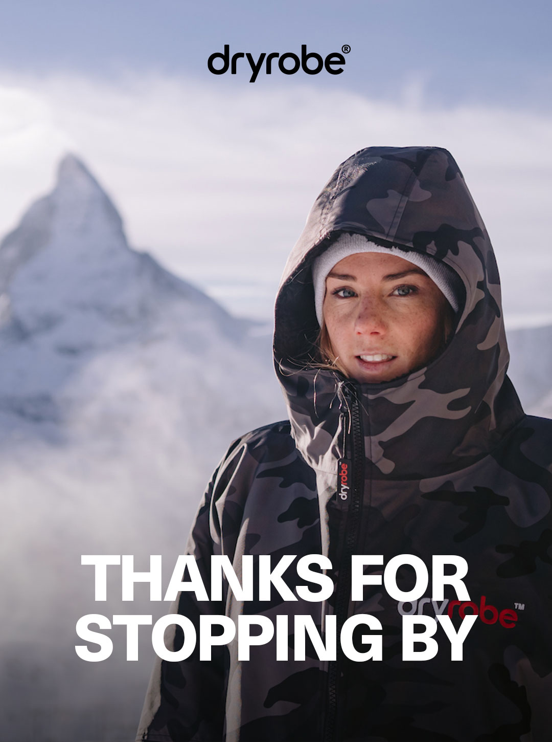 Woman wrapped up in a dryrobe® Advance with snow covered mountains in the background