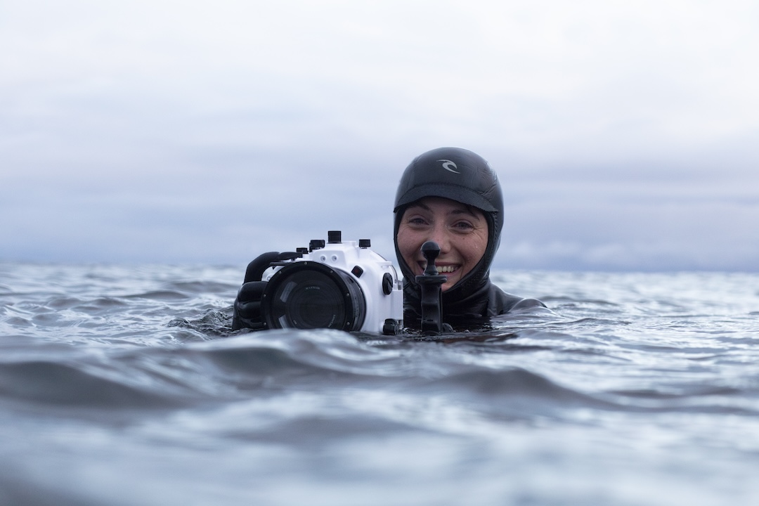 Videographer smiling in the surf with underwater camera housing