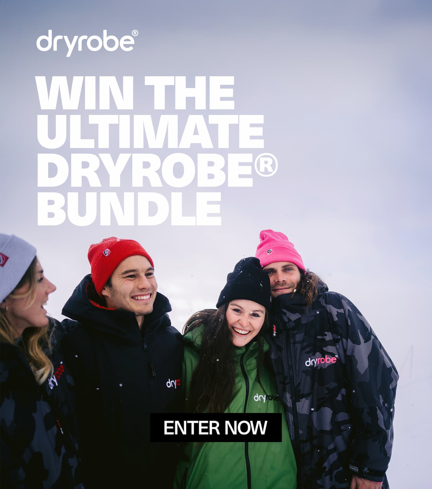 A group of friends hugging in the snow while wearing changing robes and beanies