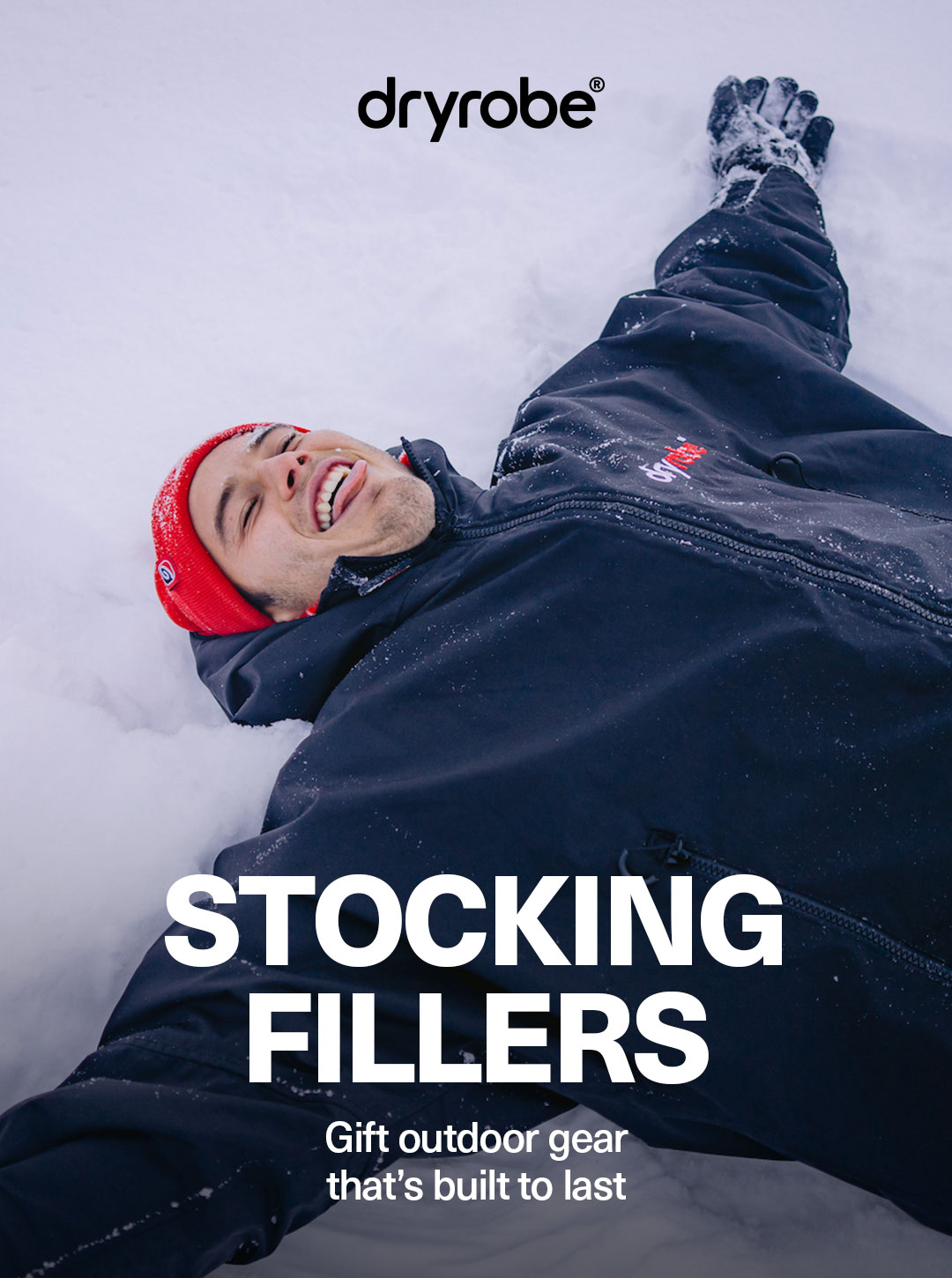 Man lying in the snow wearing a dryrobe® Advance, beanie and gloves