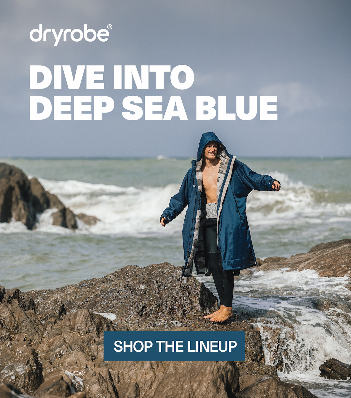 Man on the edge of the sea in a Dryrobe® Advance in Deep Sea Blue