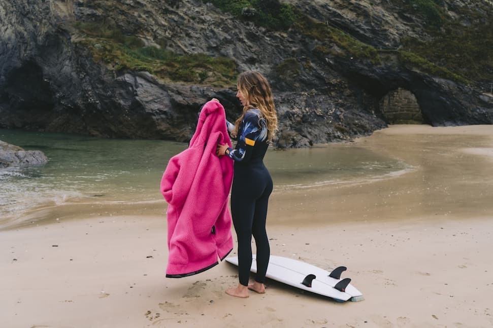 Surfer on the beach getting changed using a changing robe