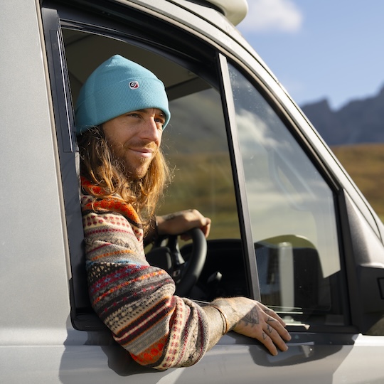 Man wearing a beanie hat while driving a camper van