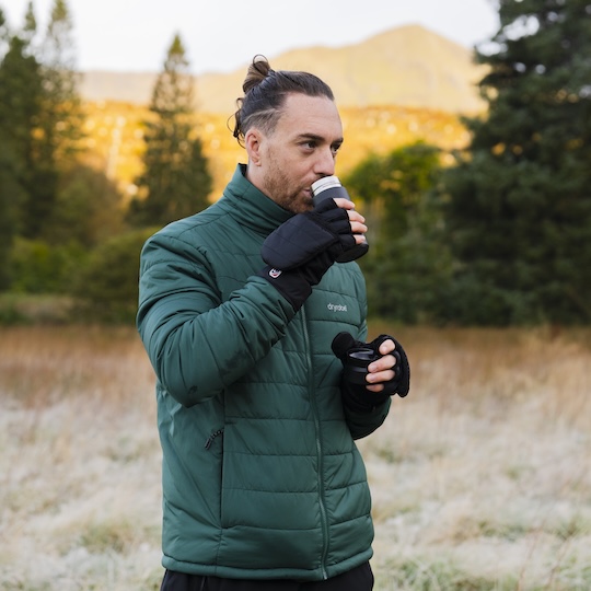 Man wearing gloves drinking out of a thermal cup in nature