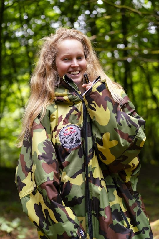 Woman wearing limited edition Red Bull Hardline Dryrobe Advance with a woodland background