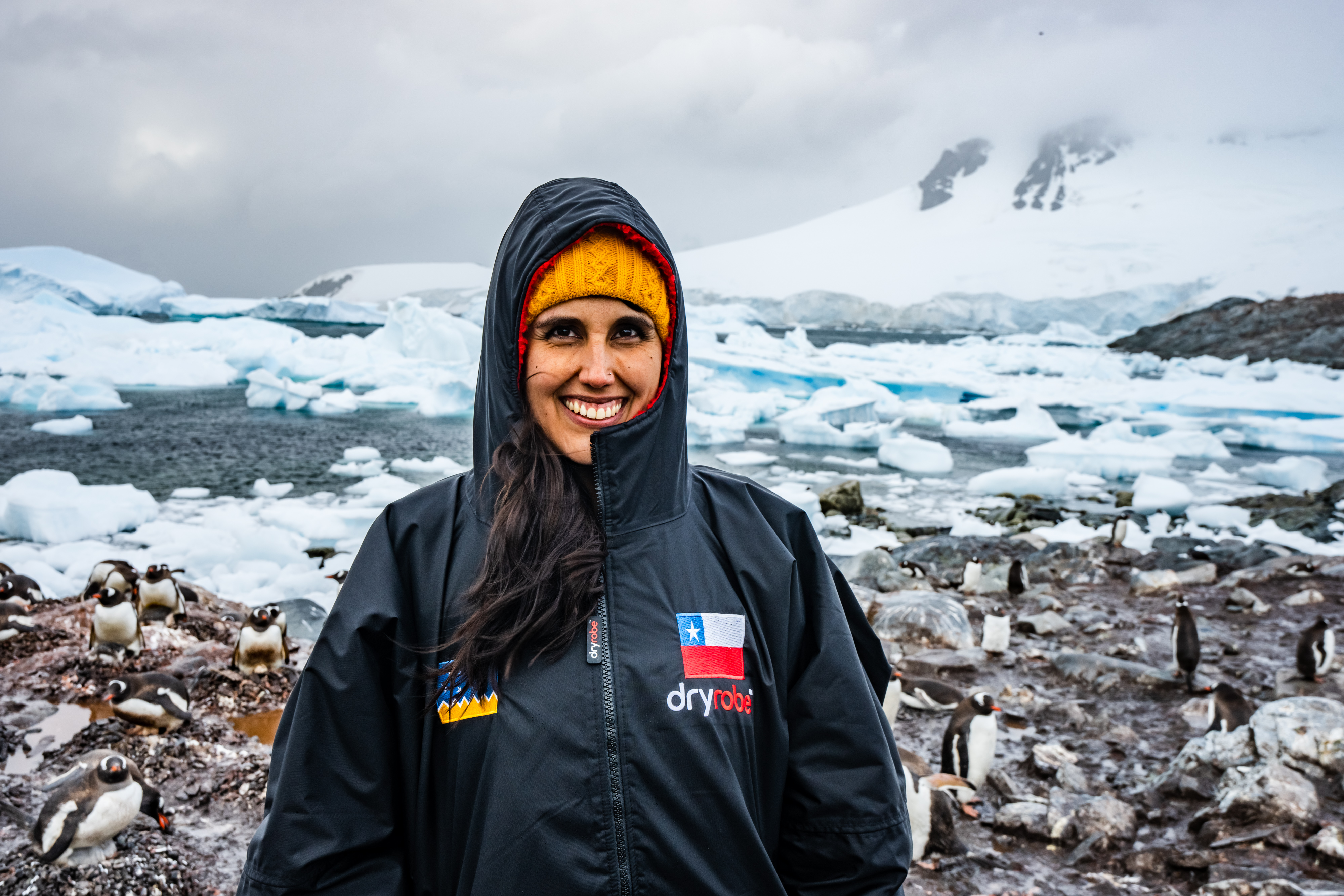 Bárbara Hernández Huerta wearing a dryrobe in Antarctica with penguins surrounding her