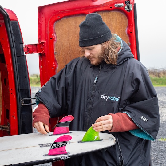 Big wave surfer Taz Knight taking his surfboard out of the back of his red van
