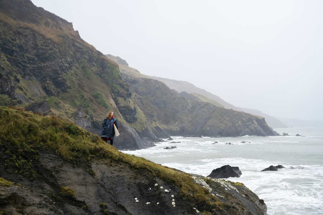 Woman standing on a rock looking out across a moody mountain range