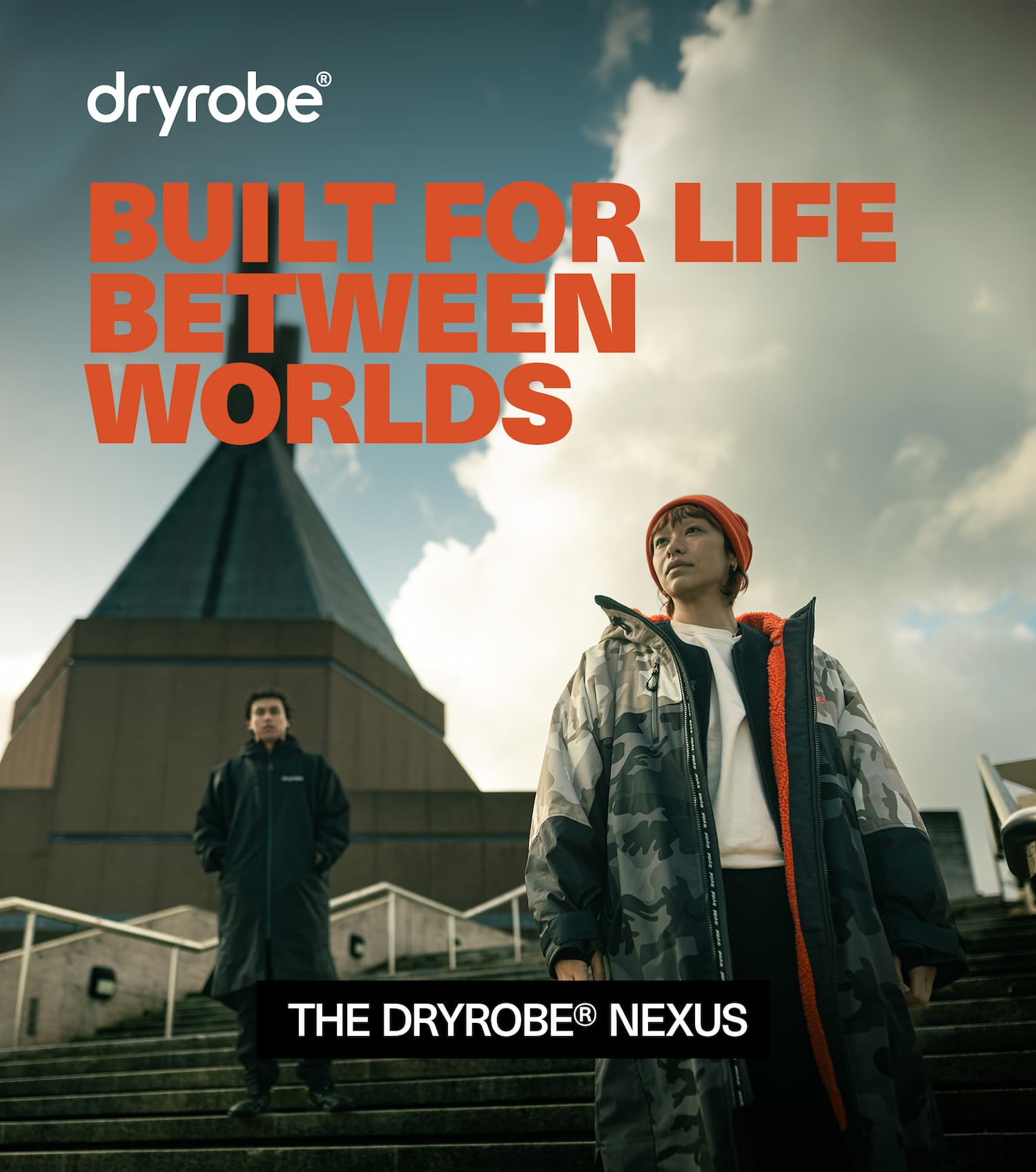 Two people wearing the Dryrobe® Nexus with a modern church in the background