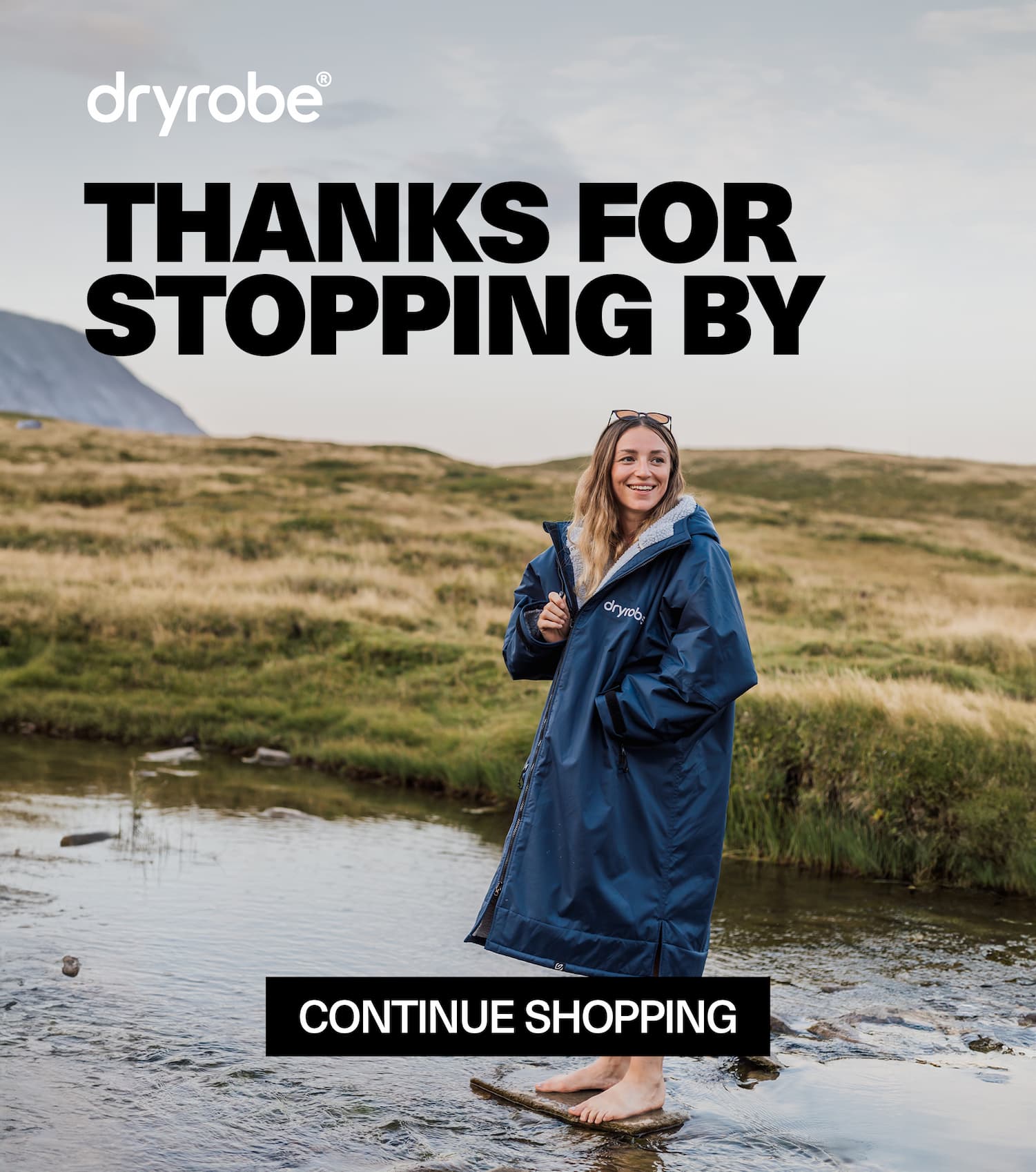 Woman wearing a Dryrobe® on a dusky evening by a lakeside