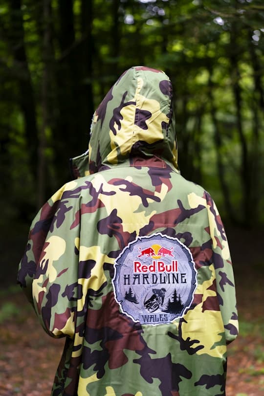 Person wearing a limited edition Red Bull Hardline Dryrobe Advance with a woodland background