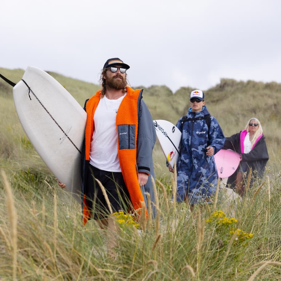 A family walking through the dunes, all wearing Adults Long Sleeve Dryrobe® Advance changing robes