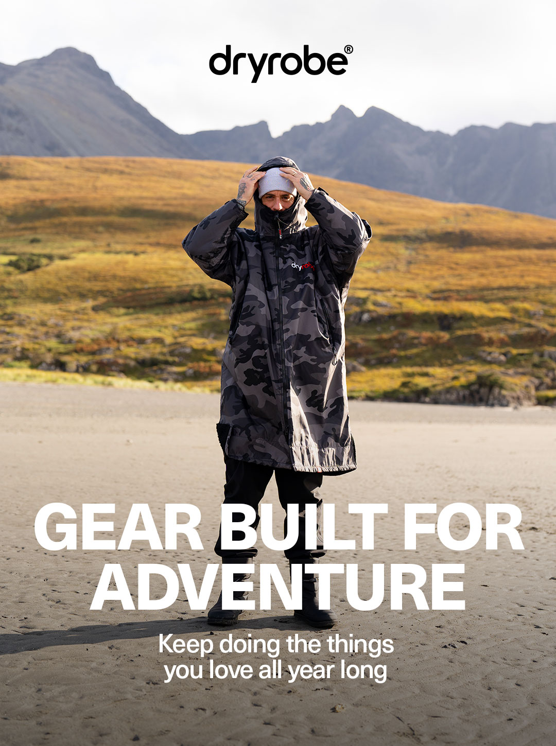 Man wearing a Dryrobe® Advance with the hood up on a beach in the Scottish Highlands