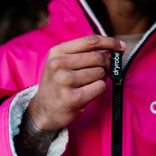 Big wave surfer Andrew Cotton wearing a dryrobe® and carrying a surfboard
