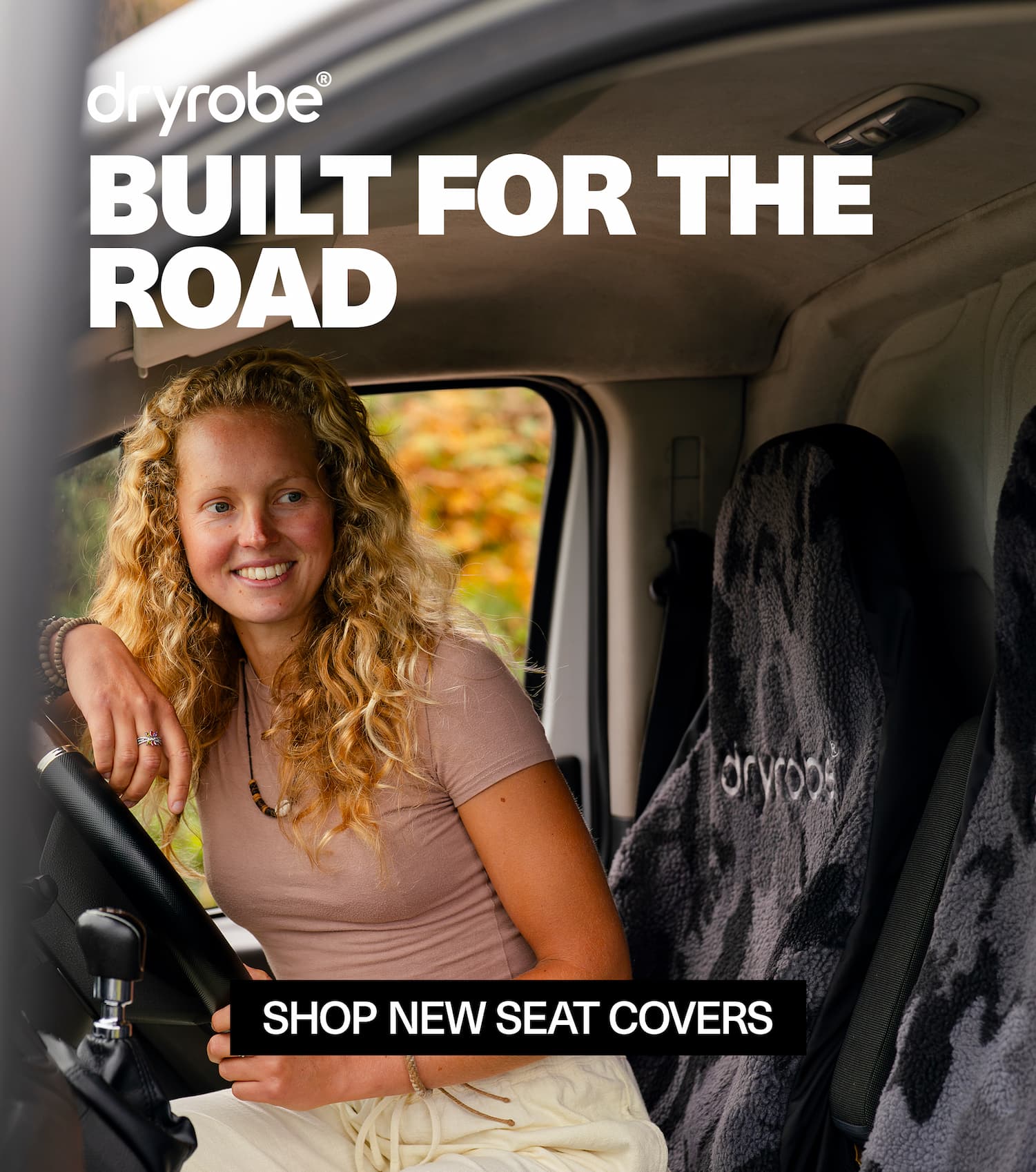 Woman sat in a camper van leaning on the steering wheel and looking out of the window