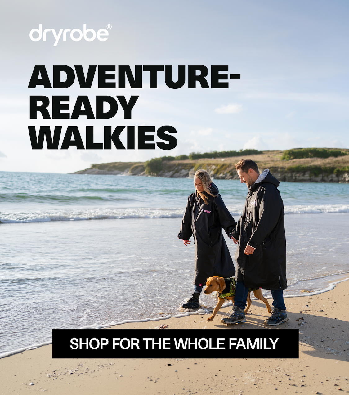Couple walking dog on the beach wearing Dryrobe® Advance