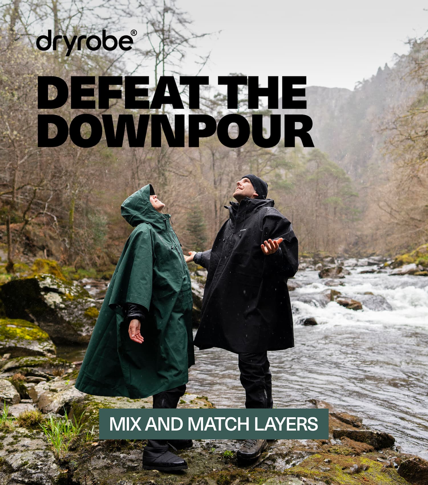 Two people stood beside a river in the rain wearing Dryrobe® ponchos