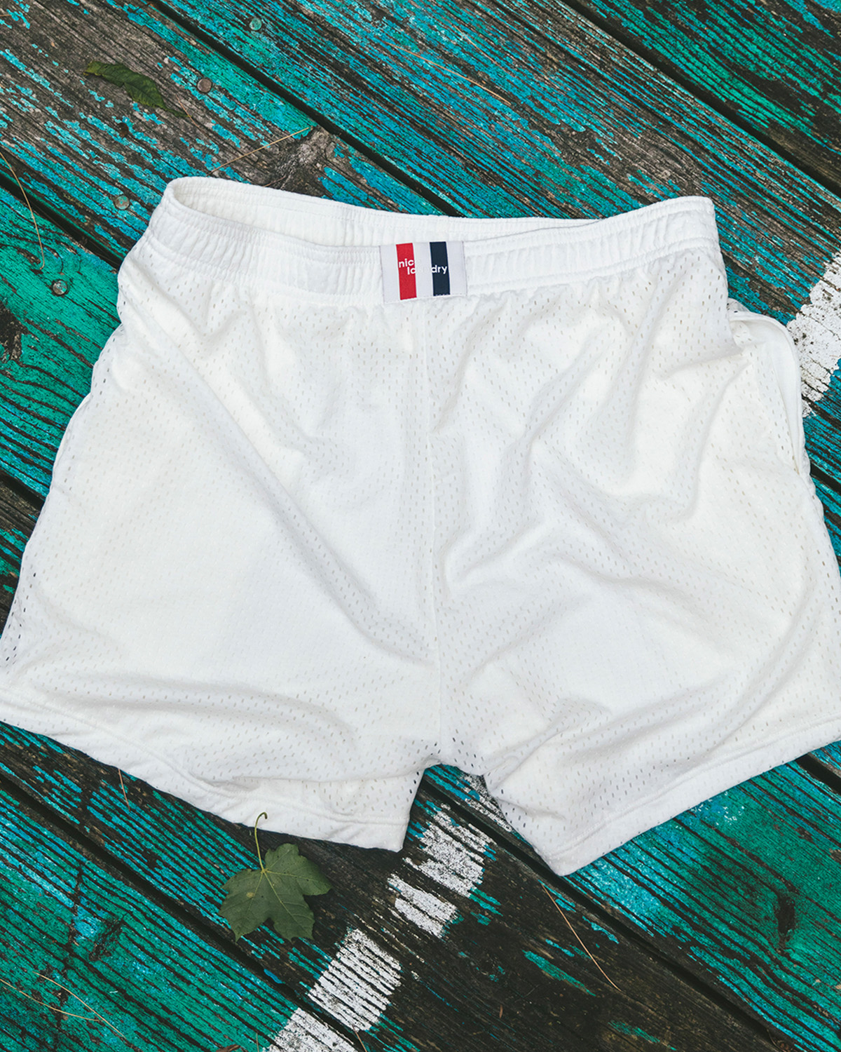 Pair of cream/white lounge shorts sitting on a lounge chair at the beach.